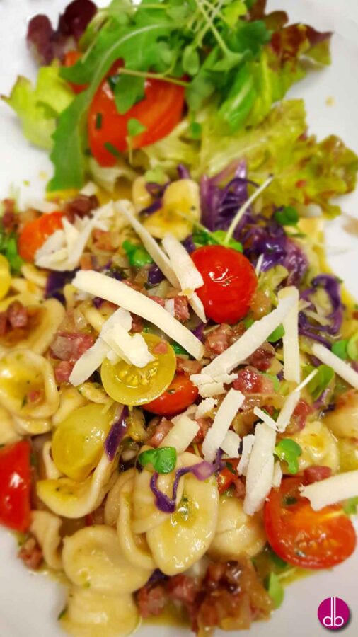 Orecchiette Pasta mit gebratenen Spitzkohl, süßen Kirschtomaten und gebratenem Bauchspeck. Dazu frisch geriebener Parmesan und frische Kräuter.